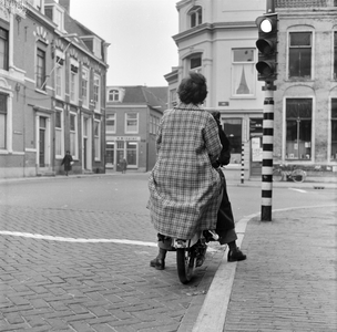 125498 Afbeelding van een bromfietser met passagier bij het stoplicht op de hoek van de Korte Nieuwstraat en het Wed te ...